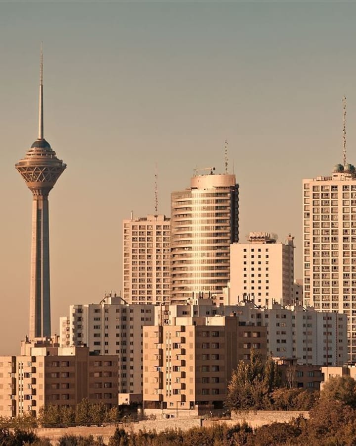 Skyline von Teheran im Abendlicht mit dem Milad-Fernsehturm und Hochhäusern.
